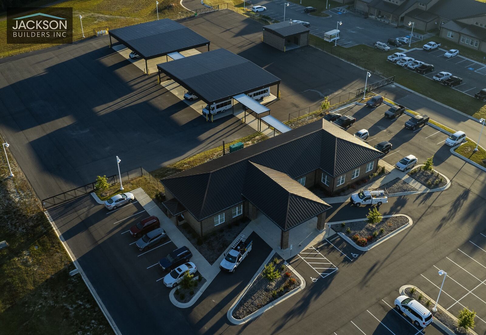An overhead view of the main building and canopy structures, with parked cars along the lot