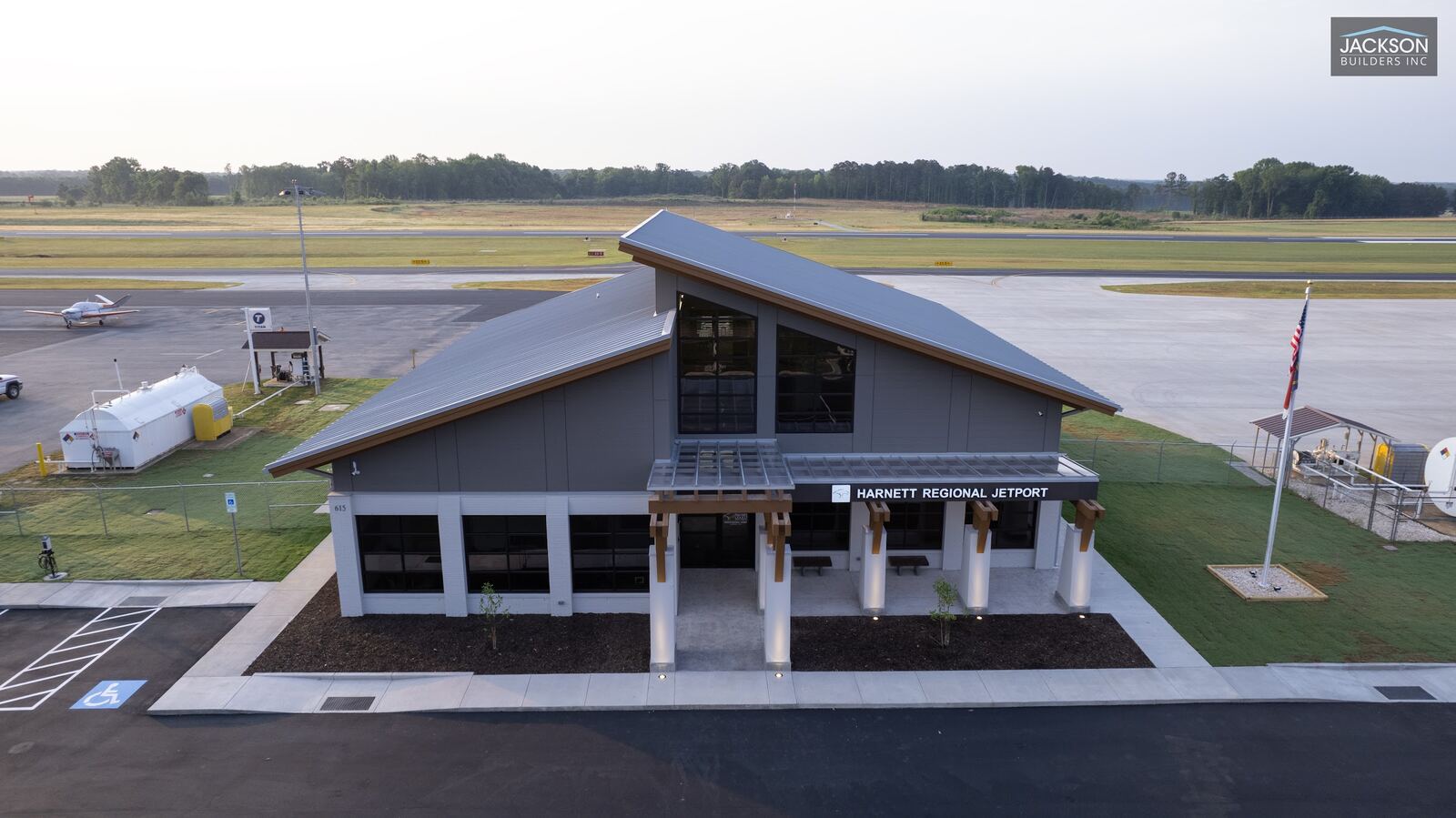The terminal and its parking lot from a high angle, with fuel tanks and hangars nearby